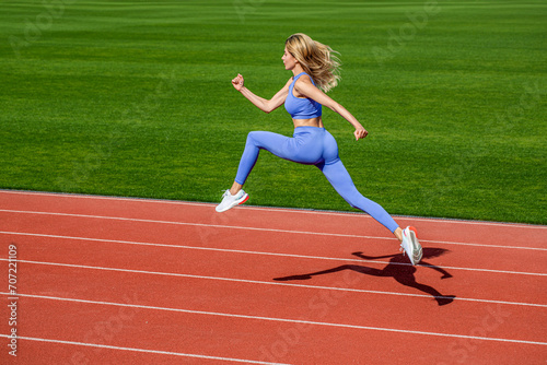 Sportswoman in sportswear jumping. Woman running during. Sport backgrounds. Runner. Professional sportswoman during running training session. Woman running jump on stadium track