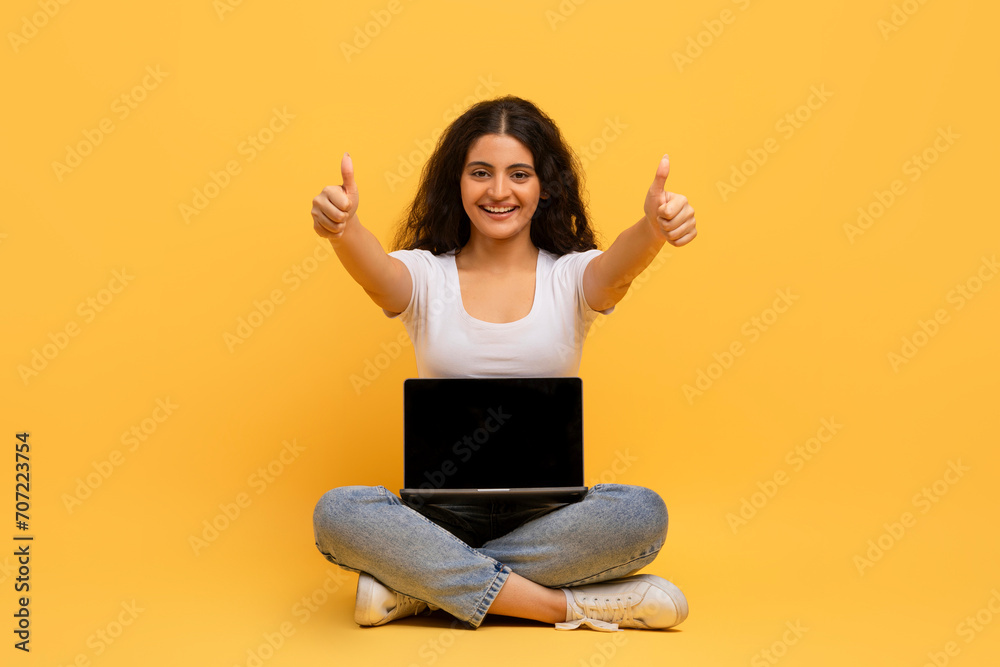 Cheerful attractive young hindu lady with laptop sitting on floor Cheerful attractive young hindu lady with laptop sitting on floor