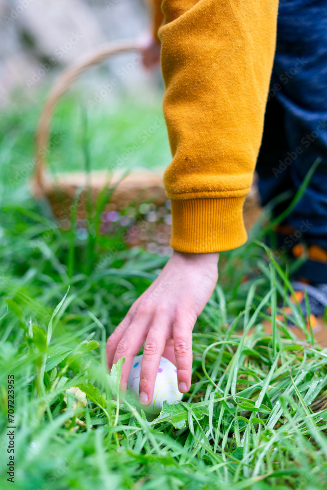 Child's hand picking up a hidden Easter egg Child's hand picking up a hidden Easter egg