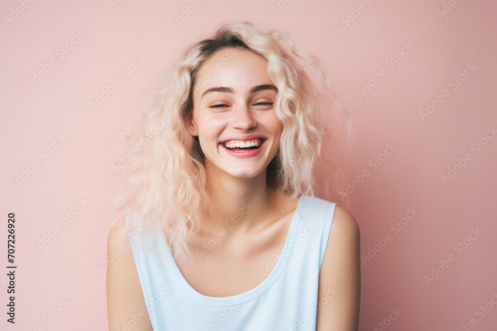 Portrait of a beautiful young woman with blond curly hair on a pink background