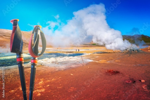 Geothermal active zone Hverir near Myvatn lake and hiking poles in Iceland, resembling Martian red planet landscape, at summer and blue sky. photo