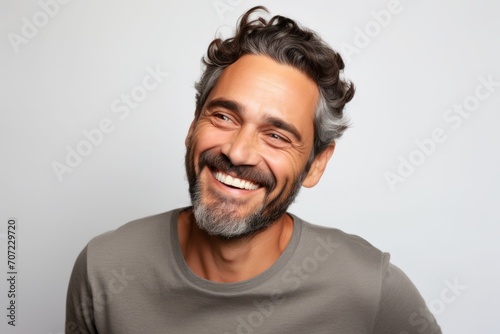Portrait of a happy man smiling and looking at the camera on a gray background © Igor