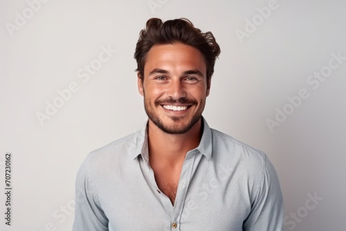 Portrait of a handsome young man smiling at the camera while standing against grey background