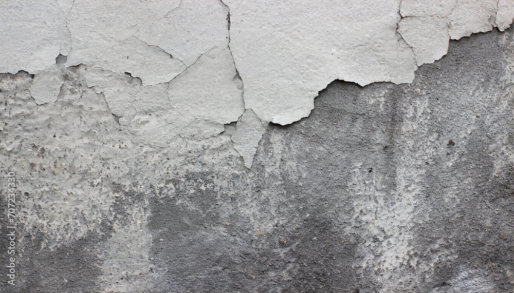 Close-up of a weathered aged, cracked concrete wall texture with peeling white paint and concrete revealing the textured surface beneath.