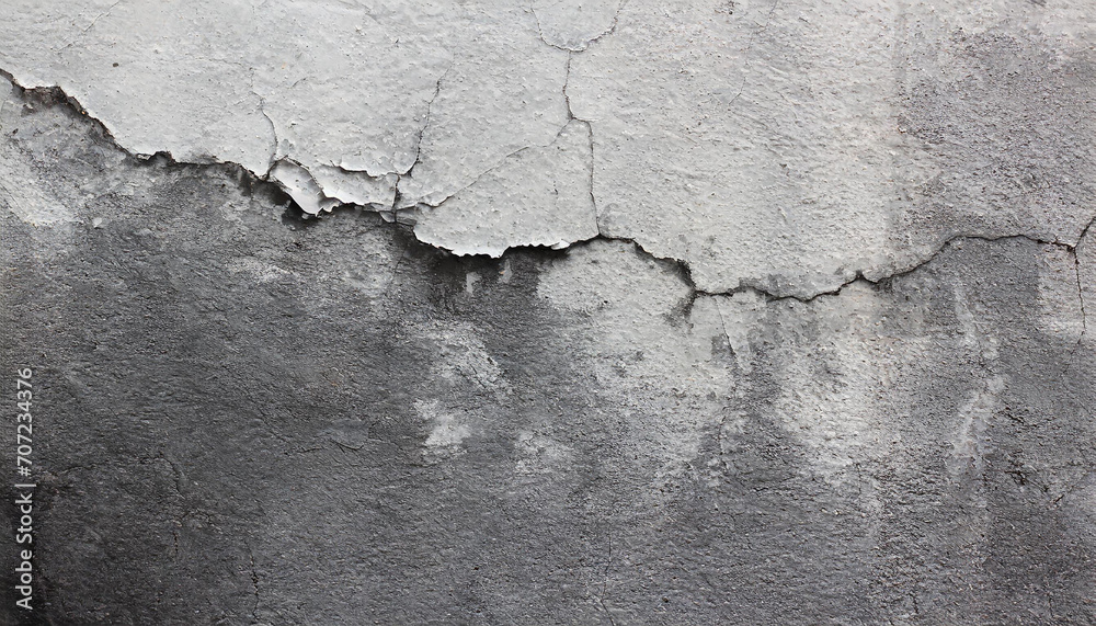 Close-up of a weathered aged, cracked concrete wall texture with peeling white paint and concrete revealing the textured surface beneath.