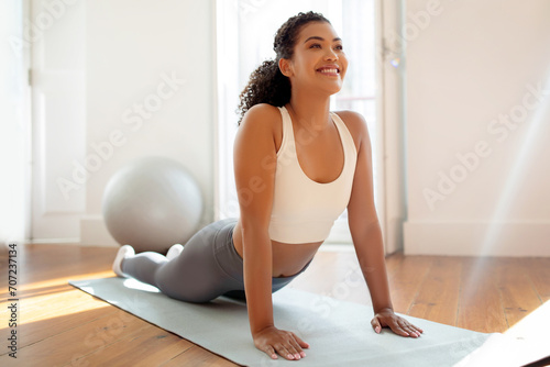 Fit woman in activewear practicing upward facing dog pose indoors photo