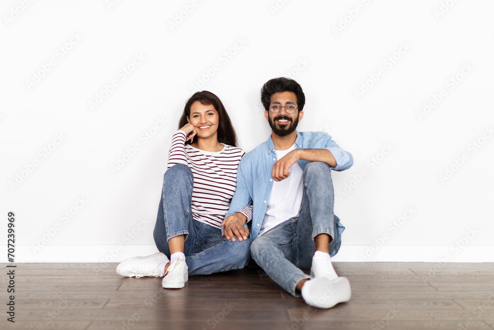 Hindu couple sitting on floor over white blank wall background Hindu couple sitting on floor over white blank wall background