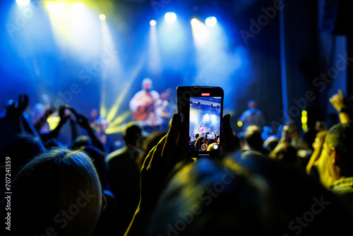 Group of People Enjoying a Live Concert with Stage Lights and Mobile Phones