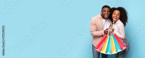 Tableau sur toile Excited african american couple with shopping spree joy, panorama with copy spac