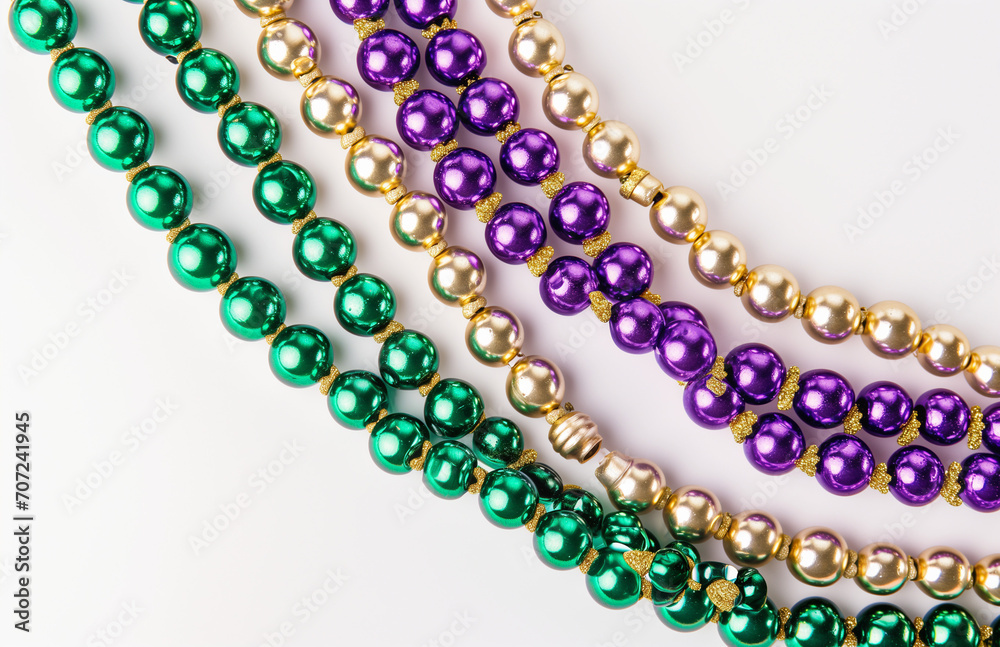 Fototapeta premium Mardi gras beads on a white background, uniformly staged, purple, green and beige