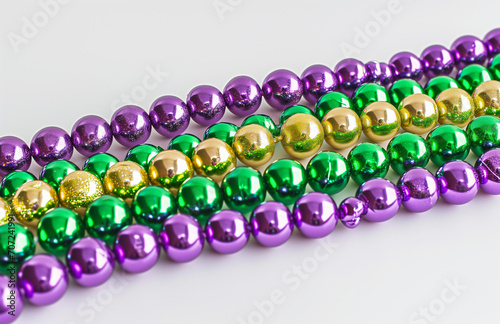 Mardi gras beads on a white background, uniformly staged, purple, green and beige