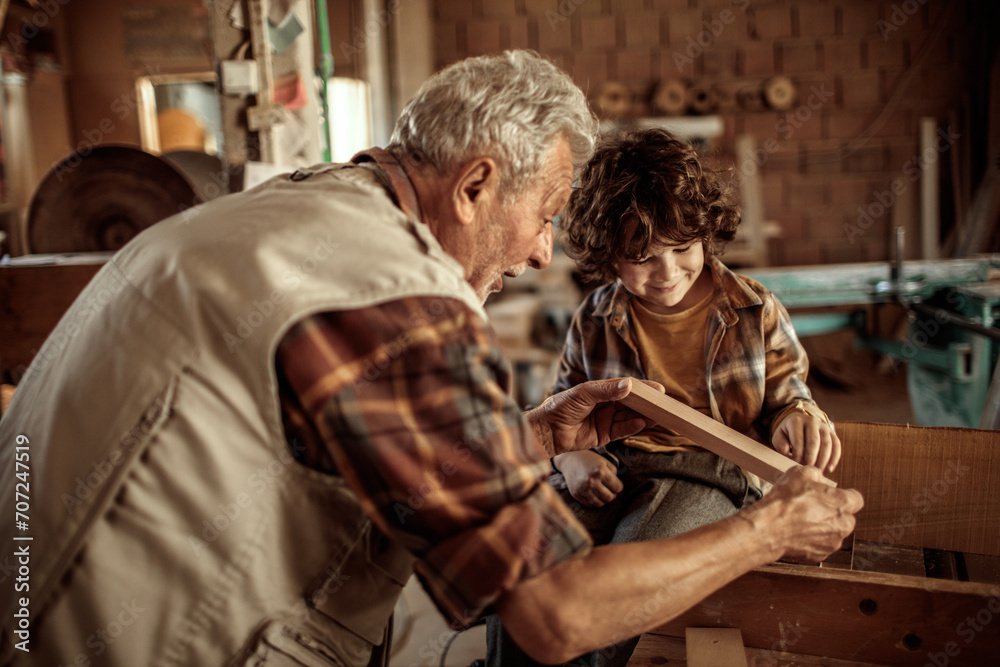 Senior man teaching grandson woodworking in workshop Senior man teaching grandson woodworking in workshop