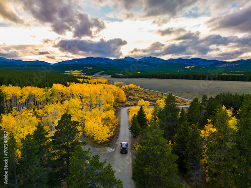 Photography Truck driving gravel road towards mountain sunset surrounded by fall color