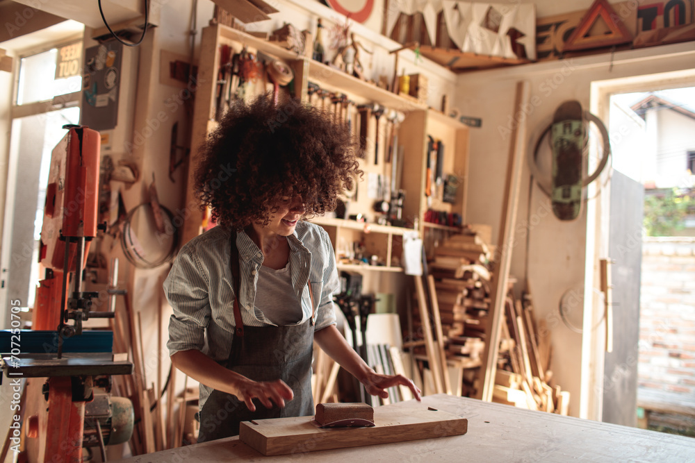 Happy female carpenter working on a woodworking project in workshop
