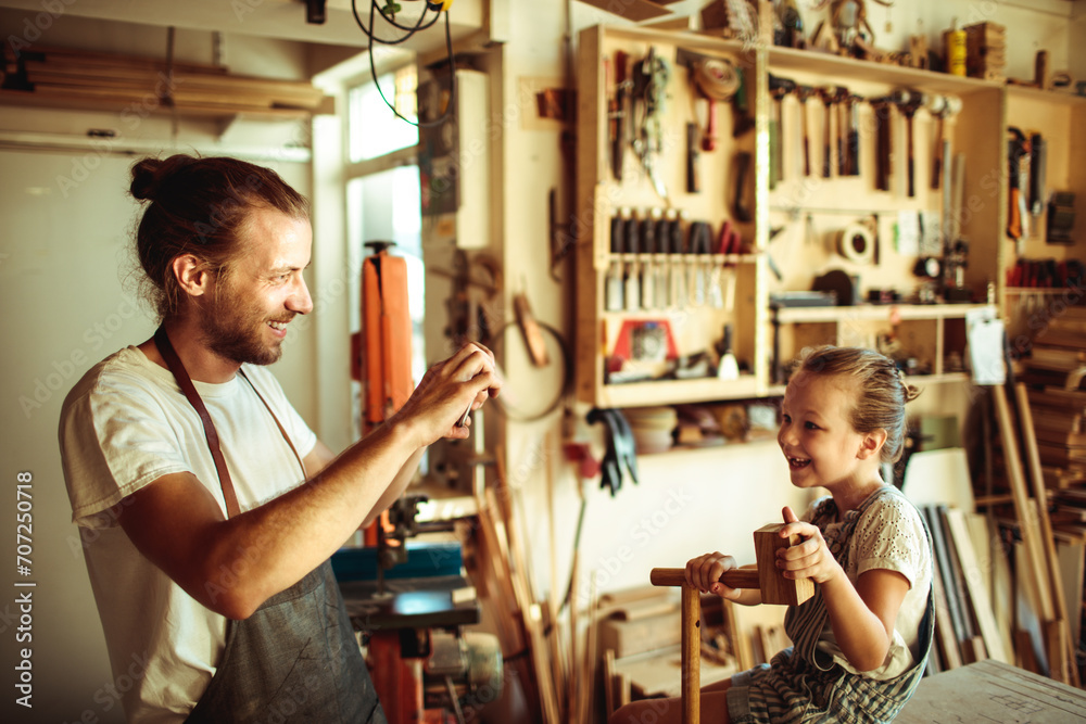 Father and daughter enjoying carpentry work together in a sunny workshop
