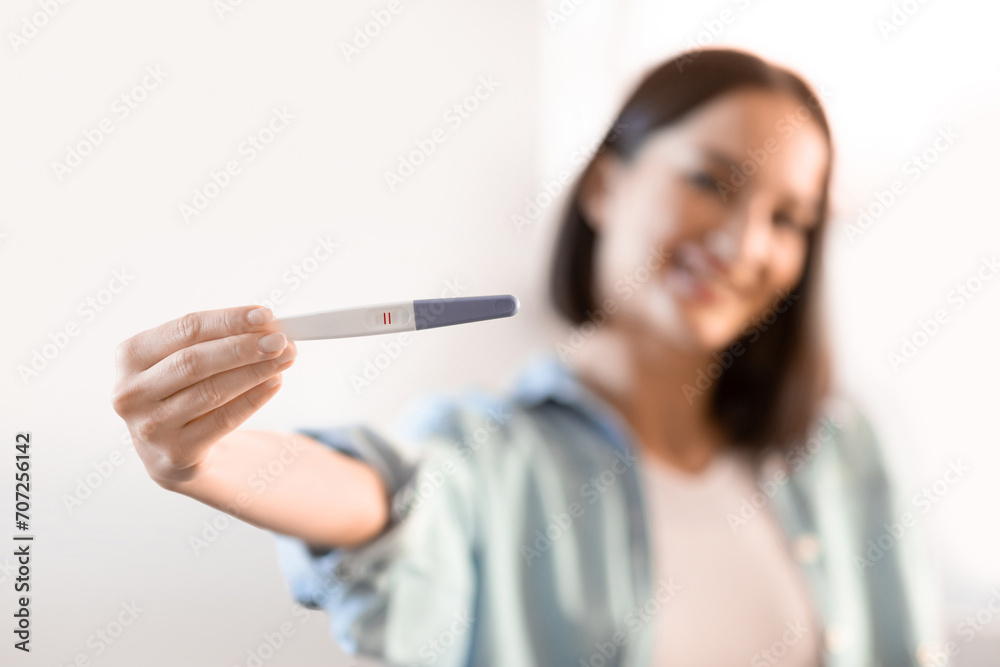 Happy young pregnant lady showing her positive pregnancy test indoor Happy young pregnant lady showing her positive pregnancy test indoor
