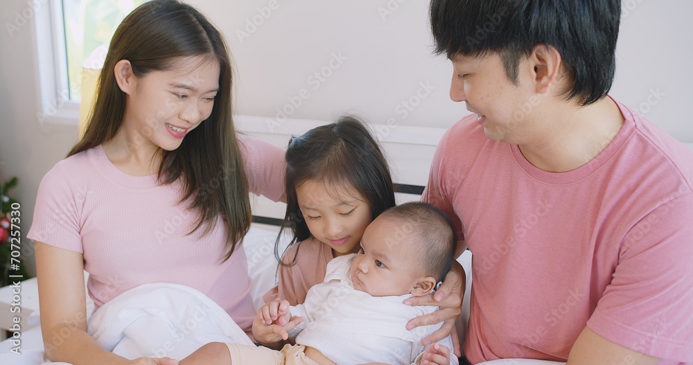 Happy Asian family father mother daughter baby embrace smiling together lying relaxing on white bed in bedroom at home, happy parent and child girl enjoy hugging having fun playing in bedroom Happy Asian family father mother daughter baby embrace smiling together lying relaxing on white bed in bedroom at home, happy parent and child girl enjoy hugging having fun playing in bedroom