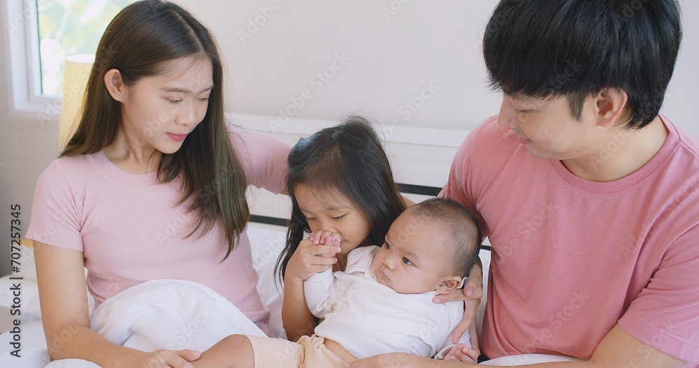 Happy Asian family father mother daughter baby embrace smiling together lying relaxing on white bed in bedroom at home, happy parent and child girl enjoy hugging having fun playing in bedroom Happy Asian family father mother daughter baby embrace smiling together lying relaxing on white bed in bedroom at home, happy parent and child girl enjoy hugging having fun playing in bedroom