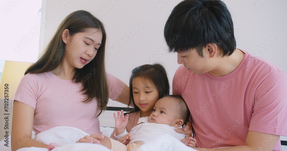 Happy Asian family father mother daughter baby embrace smiling together lying relaxing on white bed in bedroom at home, happy parent and child girl enjoy hugging having fun playing in bedroom Happy Asian family father mother daughter baby embrace smiling together lying relaxing on white bed in bedroom at home, happy parent and child girl enjoy hugging having fun playing in bedroom
