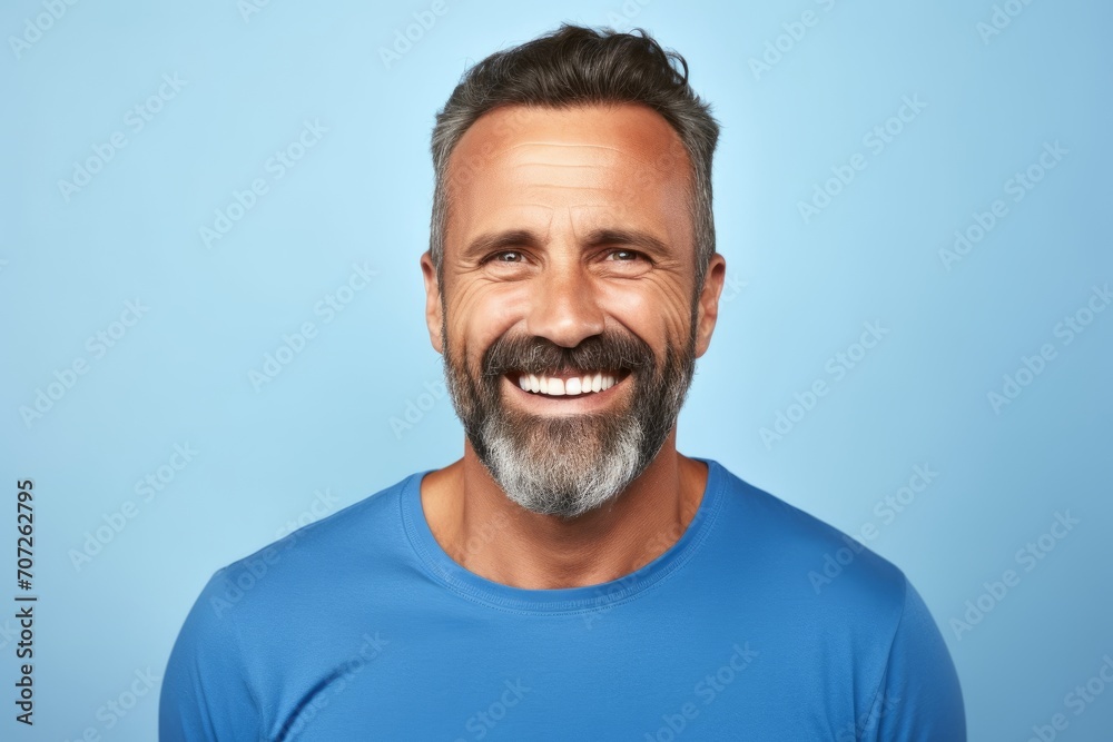 Portrait of a happy mature man with beard and mustache on blue background