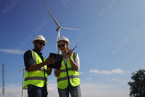 A couple of Electric engineers working together at a wind turbine farm.