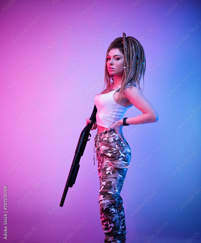a cheeky girl with braided dreadlocks on her head in neon light with an gun a cheeky girl with braided dreadlocks on her head in neon light with an gun