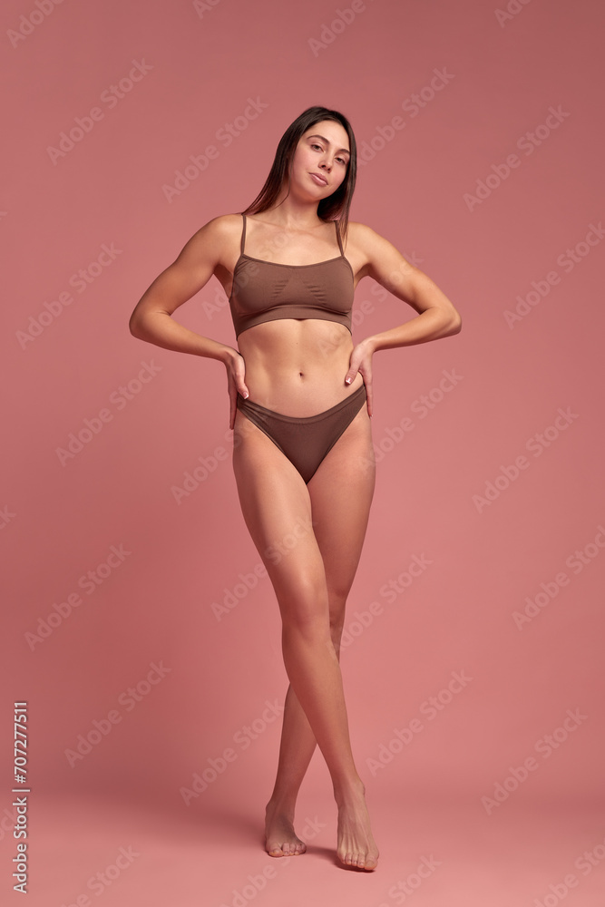 Health and nutrition. Full-length of attractive young woman with slim, healthy body standing in underwear against pink background. Concept of natural beauty, body care, diet, sport, wellness Health and nutrition. Full-length of attractive young woman with slim, healthy body standing in underwear against pink background. Concept of natural beauty, body care, diet, sport, wellness