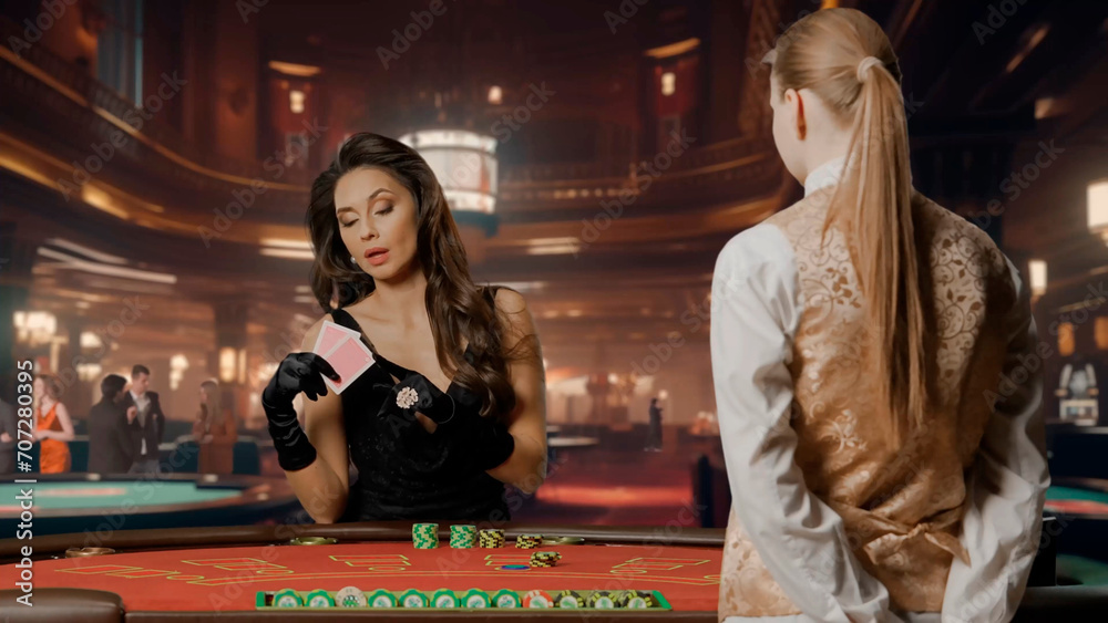 Elegant woman in black dress in casino. Attractive woman at blackjack poker table. Woman holding cards and betting with chips. Female croupier waiting for bet. Concept of casino and gambling.