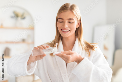 Young lady uses cotton pad and facial lotion in bathroom