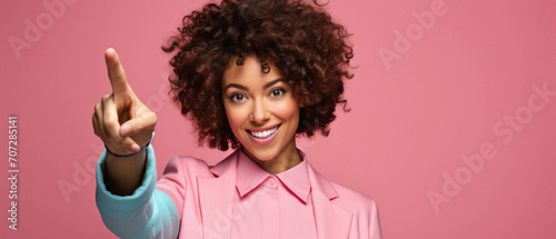 Smiling african american woman pointing finger up on pink background