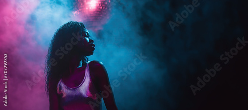Beautiful African black girl dance in nightclub beside disco ball and stage smoke in retro pint and blue light with copy space