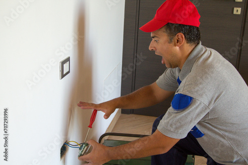 Fotografie Image of an electrician as he installs an electrical plug and gets an electric shock
