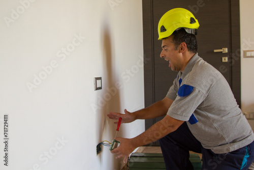 Obraz na plátně Image of an electrician as he installs an electrical plug and gets an electric shock