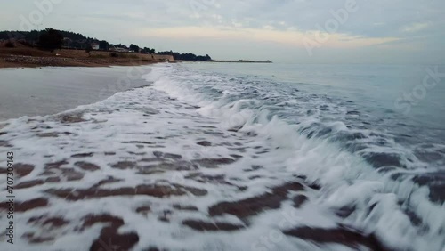 Drone soars low over beach at sunset, revealing vibrant sea, surf. Mesmerizing views of sea, surf. Stunning sea, surf, waves breaking along shoreline.