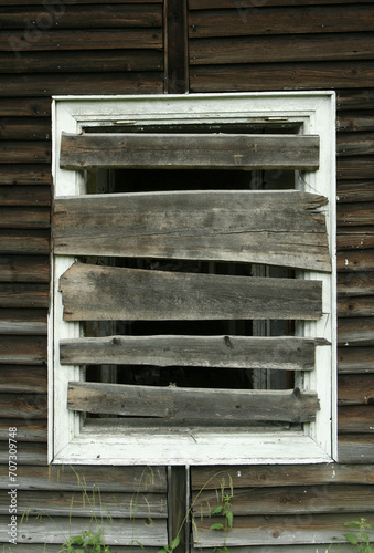 Broken  and boarded up window in worn out ruined old wooden boarding house in spa town.