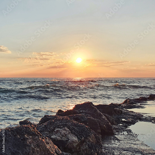 Colorful sunset with large sun under the sea waves.