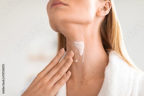 Cropped of blonde lady applying cream moisturizing her neck indoor
