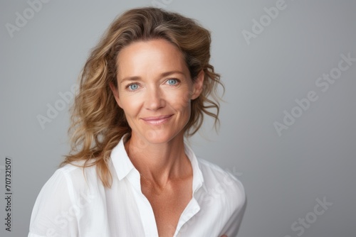 Portrait of a happy mature businesswoman standing against grey background.