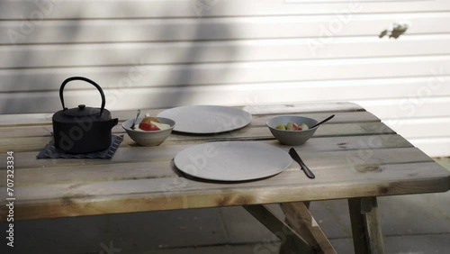 A picknick table set for breakfast in the shade on a sunny day