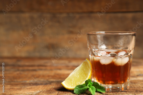 Glass of rum with lime an mint leaves on wooden background