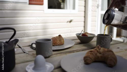 Coffee being poured from a french press during breakfast outside