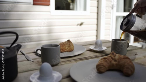 Coffee being poured from a french press during breakfast outside
