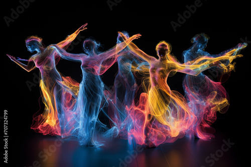 Silhouettes of group dancing people in colored smoke or shine on black background. Abstract luminescent dance