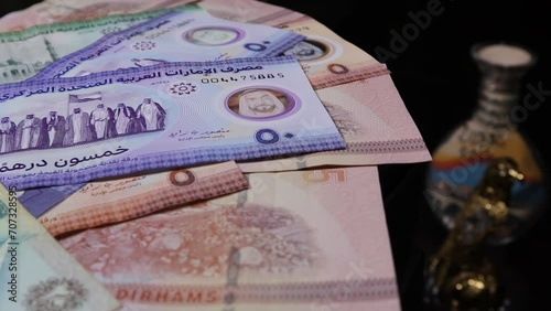 UAE Dirham banknotes rotate on an automatic table with the background of traditional handicrafts and symbols of Arabian culture.  