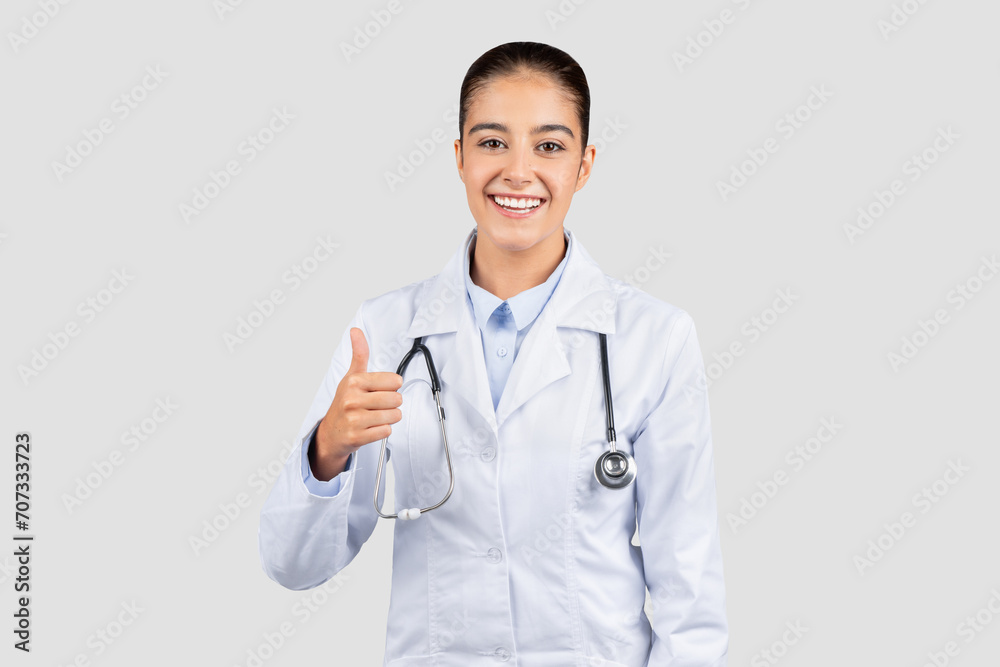 Positive Caucasian millennial doctor giving a thumbs up, wearing a lab coat with a stethoscope Positive Caucasian millennial doctor giving a thumbs up, wearing a lab coat with a stethoscope