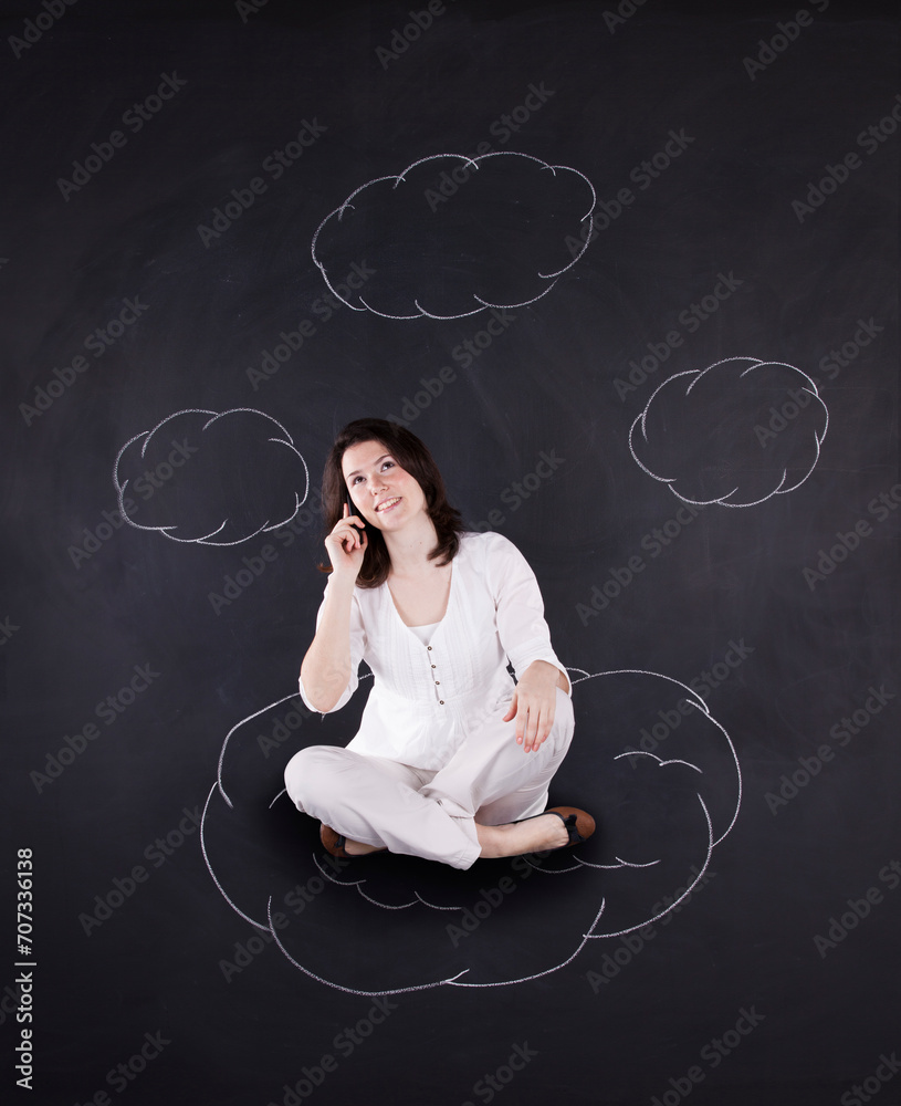 Floating businesswoman stands beside a chalkboard adorned with whimsical clouds.