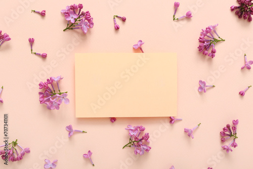 Blank card and beautiful lilac flowers on pale pink background