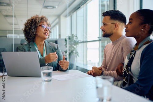 Female bank manager advising young couple during meeting in office.