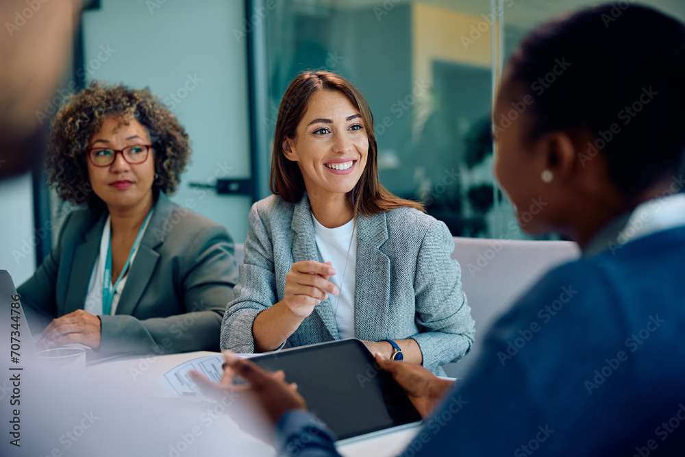 Happy businesswoman talking to her colleagues during meeting in office. Happy businesswoman talking to her colleagues during meeting in office.