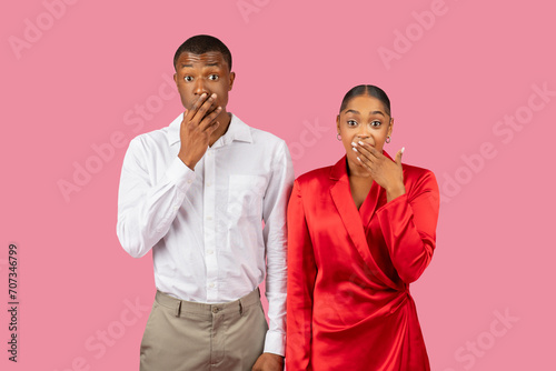 Shocked black man and woman covering mouths, white shirt, red dress